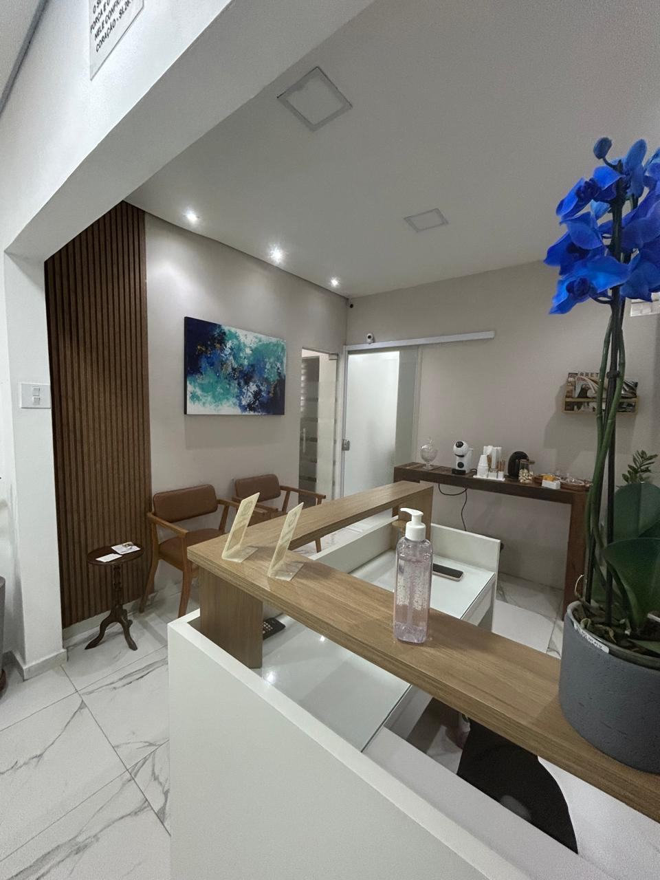 Recepção com balcão de madeira, painel ripado, poltronas e quadro em tons de azul