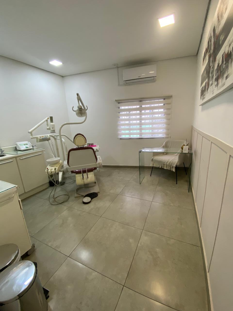 Sala de atendimento ampla e climatizada, com janela e mesa de vidro